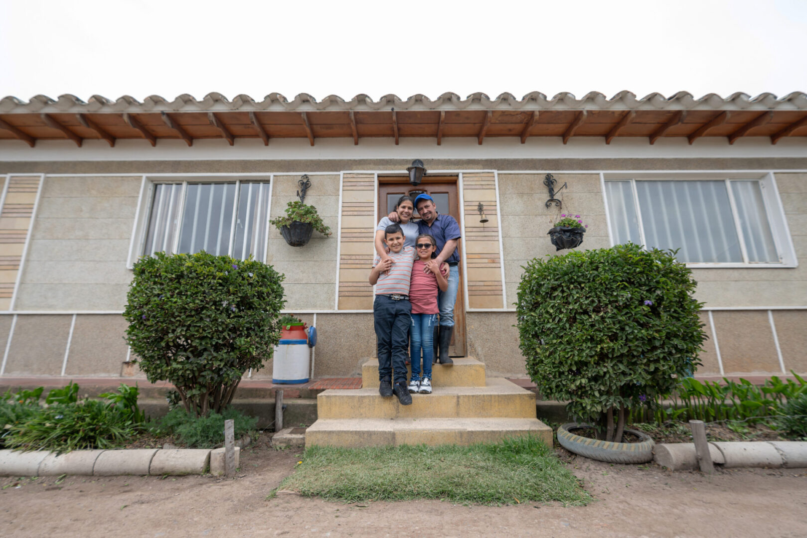 Happy Latin American family smiling in front of their new rural house - housing policy concepts