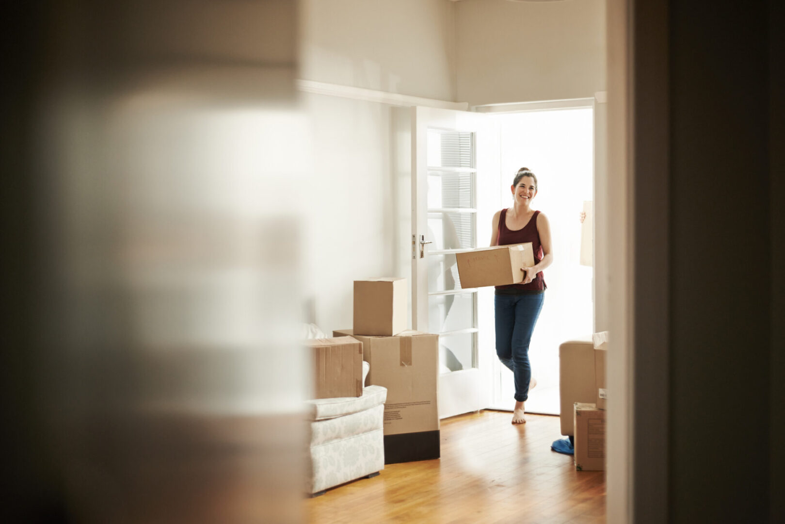 Shot of a woman carrying boxes into her new place